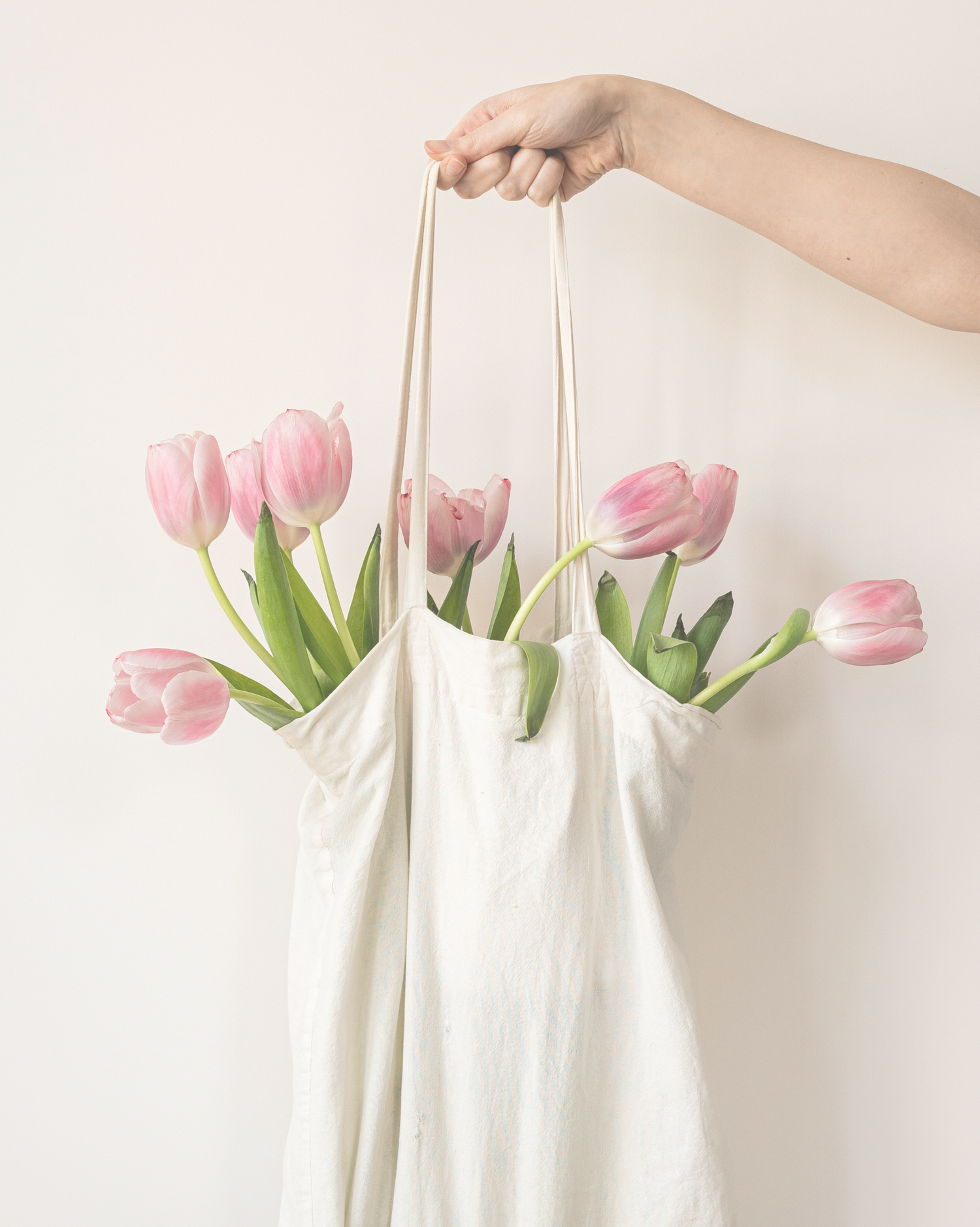 Person holding a white bag with pink tulips against a light background, featuring the brand 'Flower & Flour'.